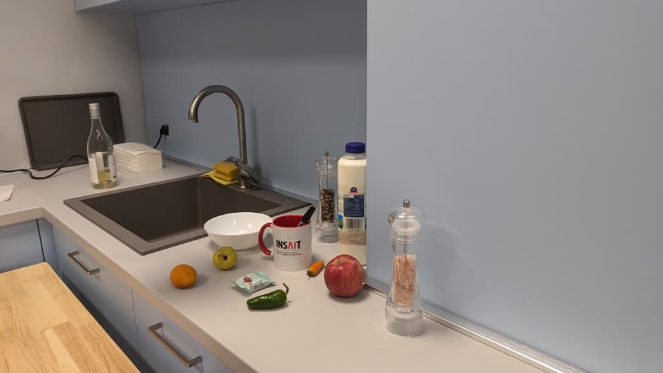 A kitchen counter with a mug, a bowl, fruit, a pepper mill and a bottle.